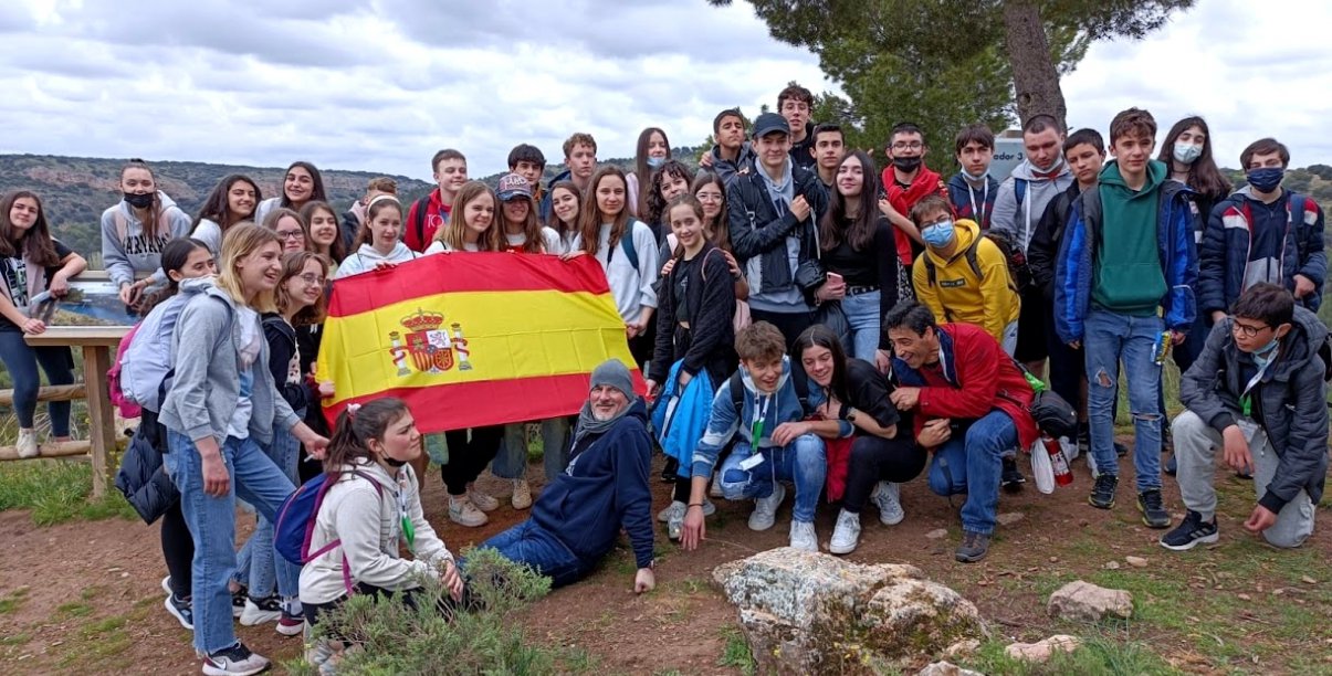 Grupowe zdjęcie kilkunastu osób w górach i flaga Hiszpanii