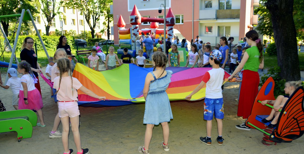 Dzieci trzymające kolorową tkaninę, plac zabaw 