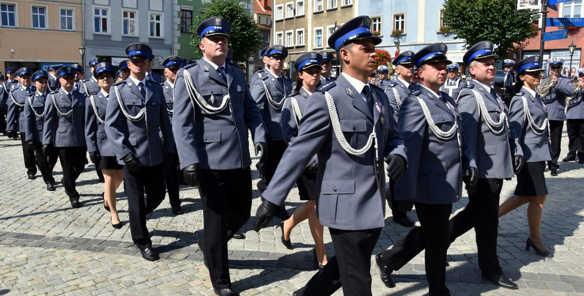 Plicjanci idący w szyku przez rynek 