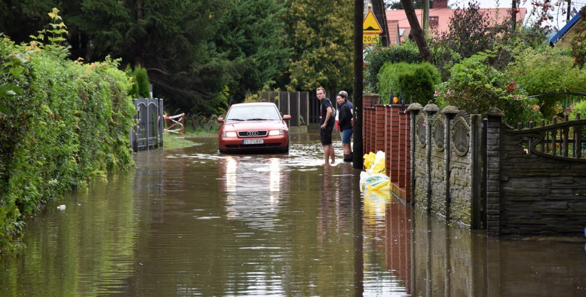 Zalana droga i jadące przez nią auto