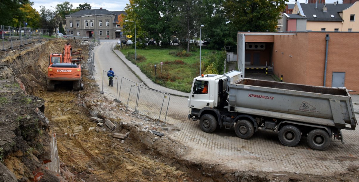 Koparka i auto ciężąrowe stojące przy remontowanej drodze