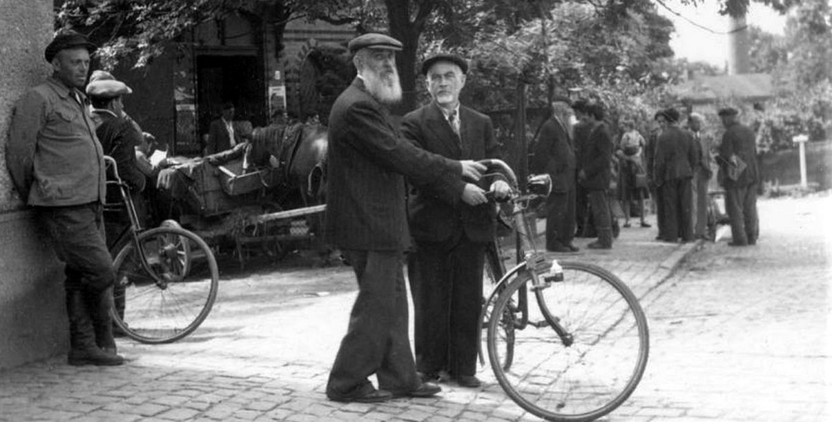 Stare zdjęcie, mjężczyźni stojący przy rowerze 
