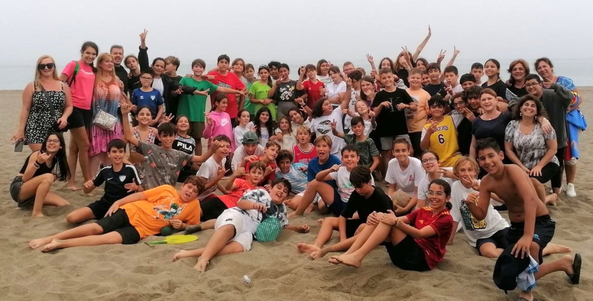 Kilkadziesiąt osób na grupowym zdjęciu na plaży