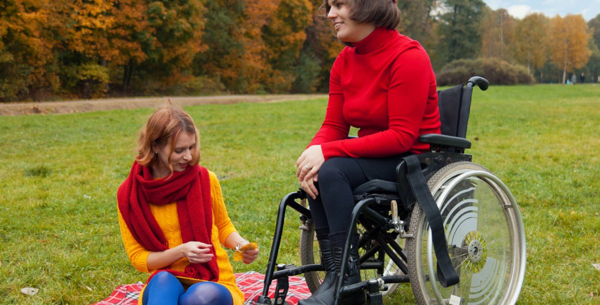 Dwie kobiety na łące na pikniku, jedna na wózku