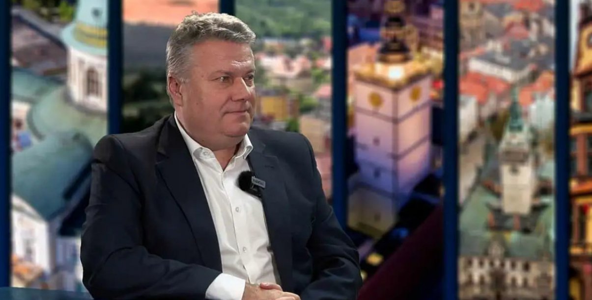 Mężczyzna w garniturze i białej koszuli siedzący przy stole