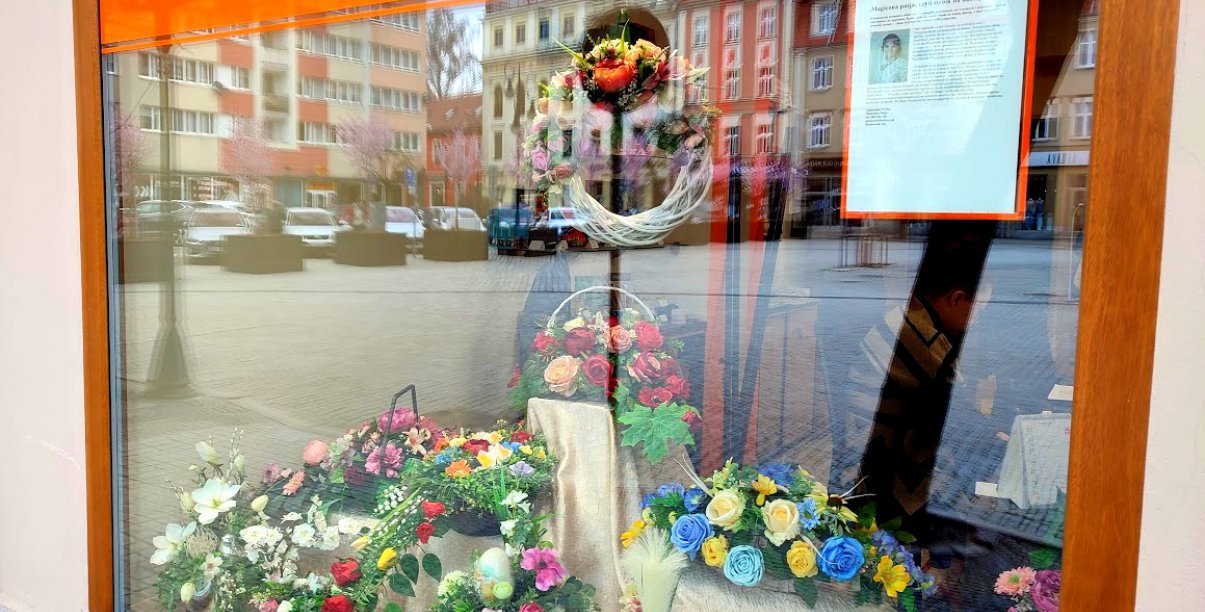 okno artystyczne ratusza a w nim kompozycje kwiatowe