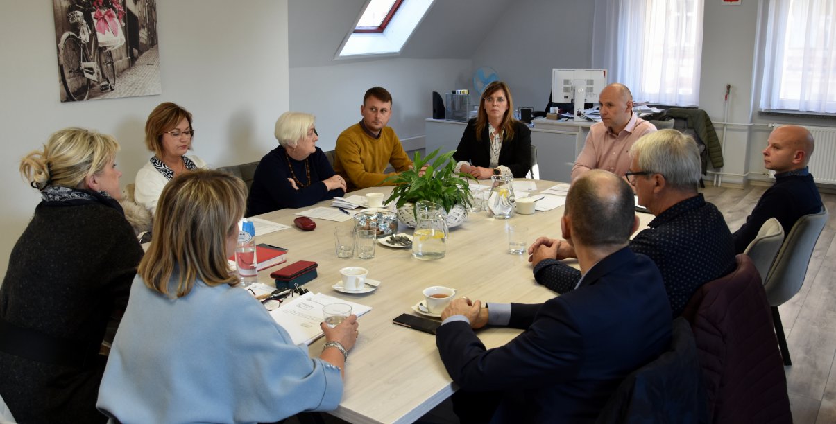 Grupa osób siedząca przy stole w jasnym pomieszczenu