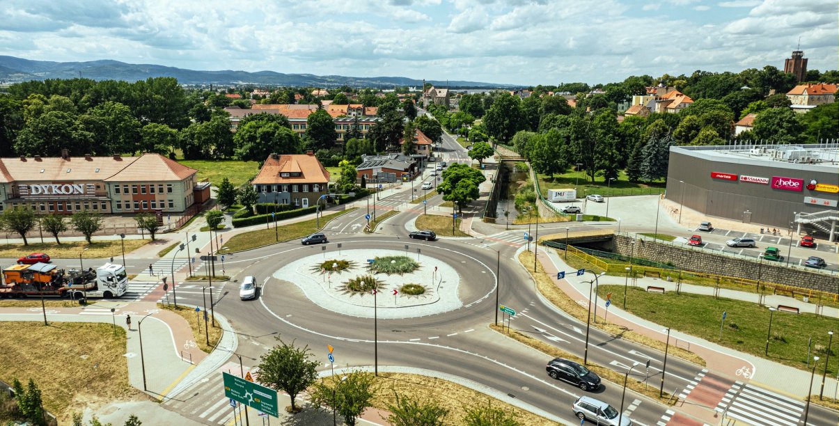 Duże rondo widziane z góry, obok budynki, na drugim planie dużo zieleni