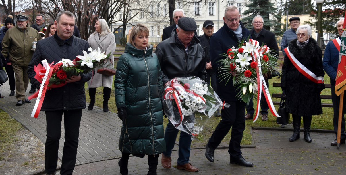 Grupa osób składająca wieńce przed pomnikiem