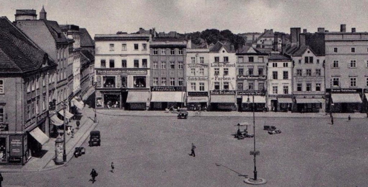 Przedwojenny rynek, kamienice, na parterach markizy, na rynku stojące stare automobile