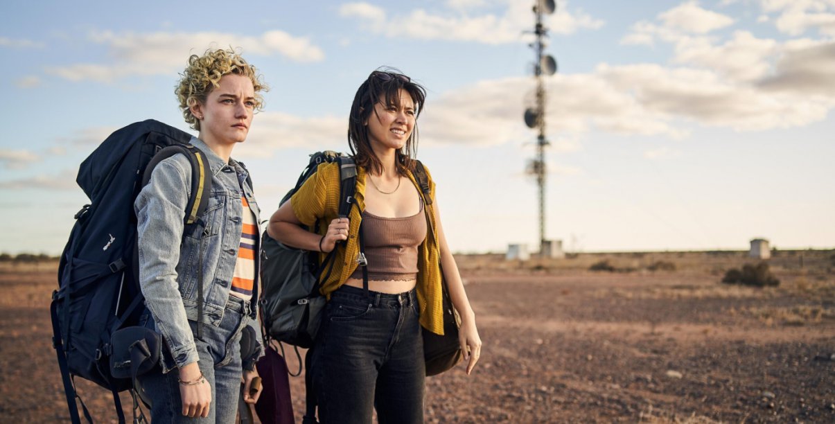 Kadr z filmu, dwie dziewczyny z plecakami turystycznymi, za nimi pustynny krajobraz