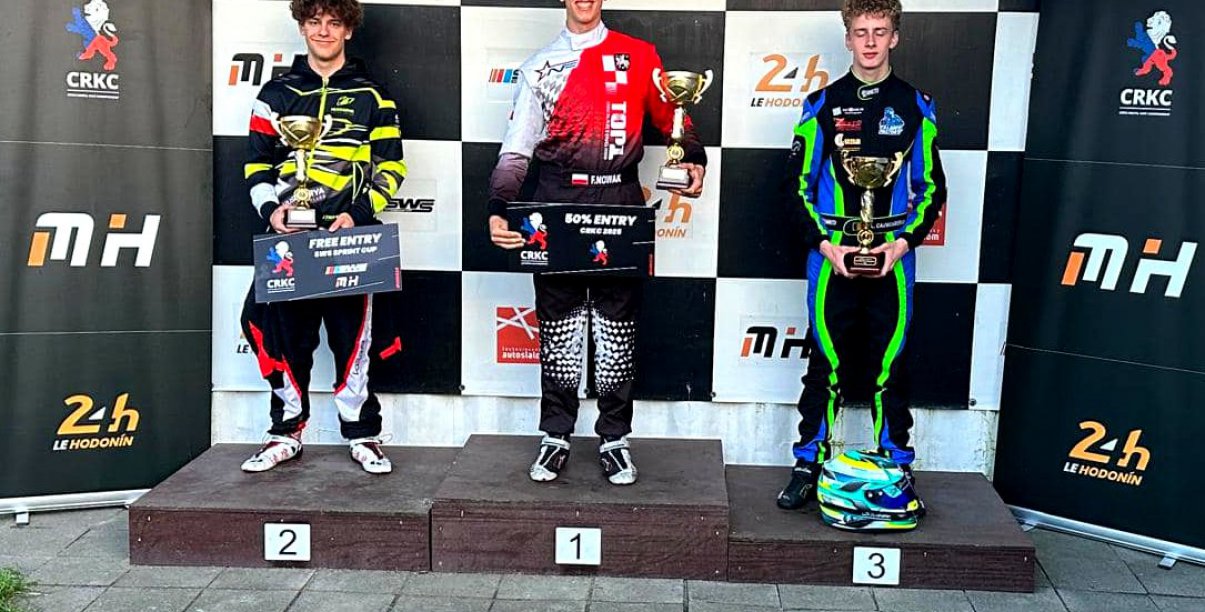Trzech młodych kierowców w kombinezonach do ścigania na podium
