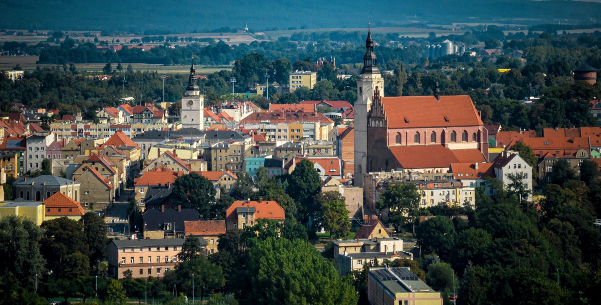 Starówka Dzierżoniowa z lotu ptaka, na pierwszym plane duży średniowieczny kościół, w tle góry