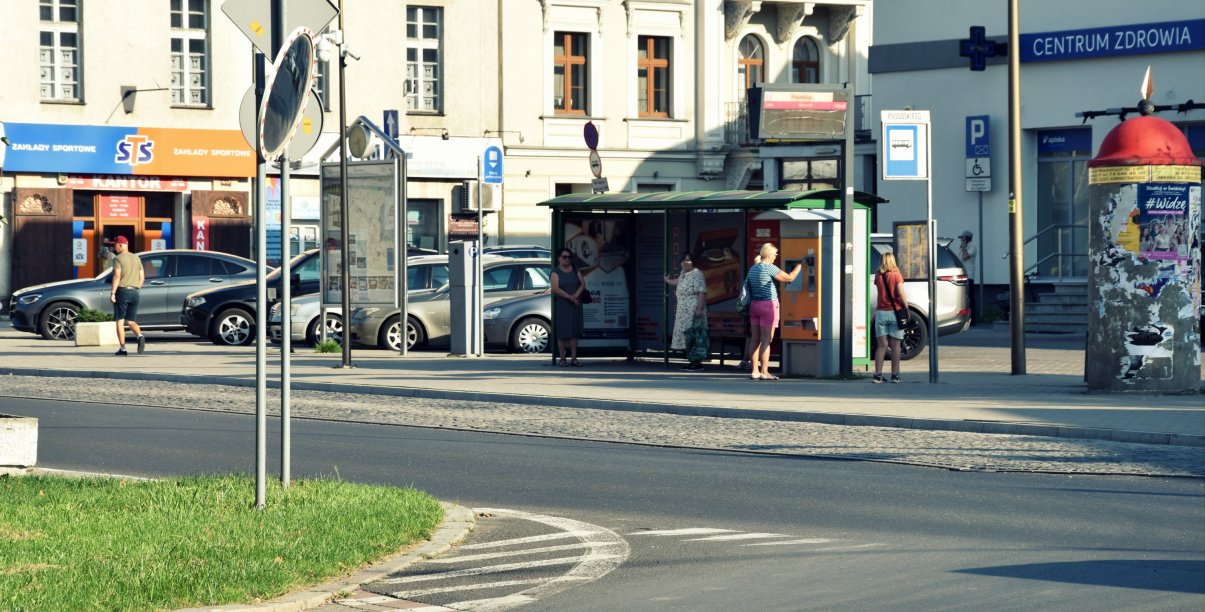 Przystanek autobusowy, na przystanków kilka osób czekających na autobus