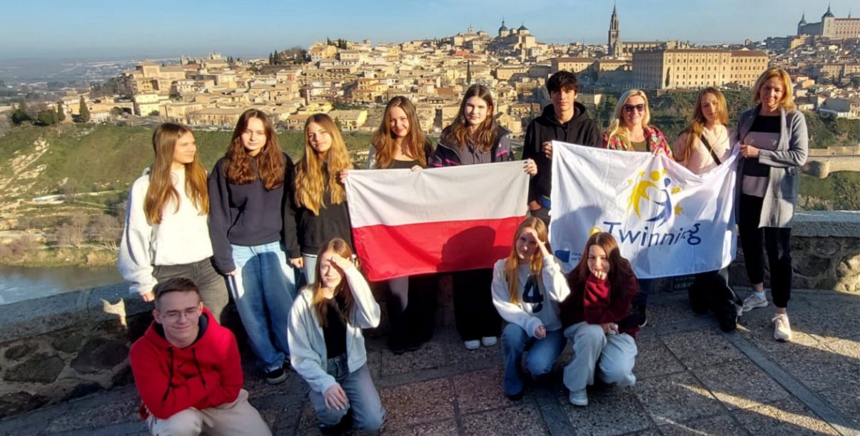 Grupowe zdjęcie uczniów SP9 z flagą Polski na tle panoramy zabytkowej starówki