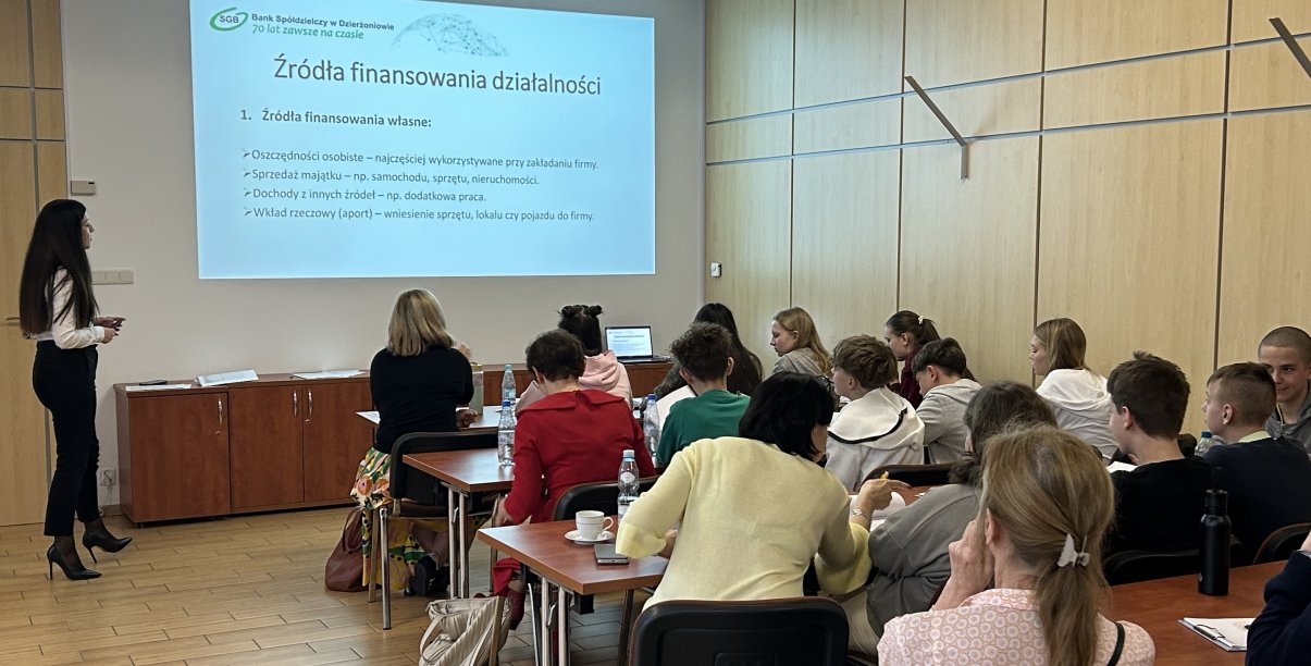 Uczniowie siedzący w ławkach podczas wykładu o przedsiębiorczości