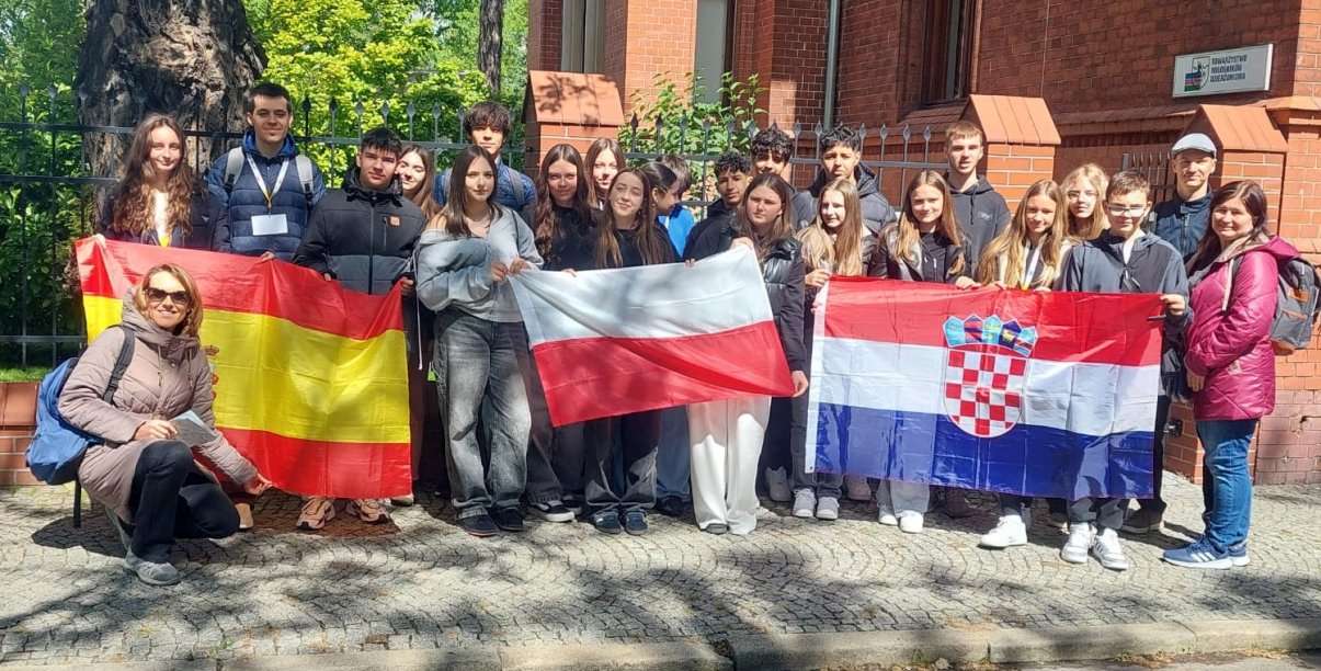 Grupowe zdjęcie uczniów trzymających flagi Polski, Chorwacji i Hiszpanii