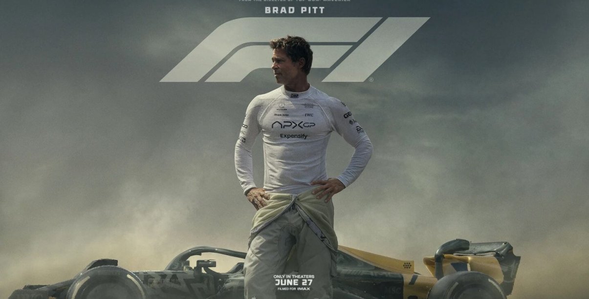Mężczyzna w białej koszulce, za nim bolid formuły F1