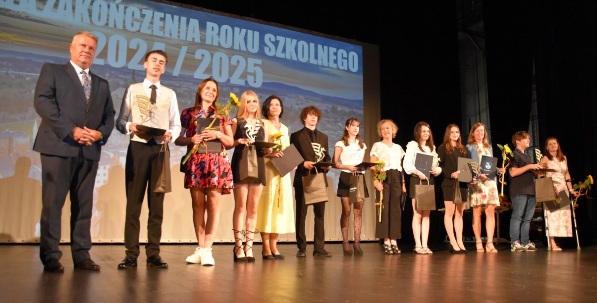 Kilkunastu uczniów na scenie na wspólnym zdjęciu z burmistrzem