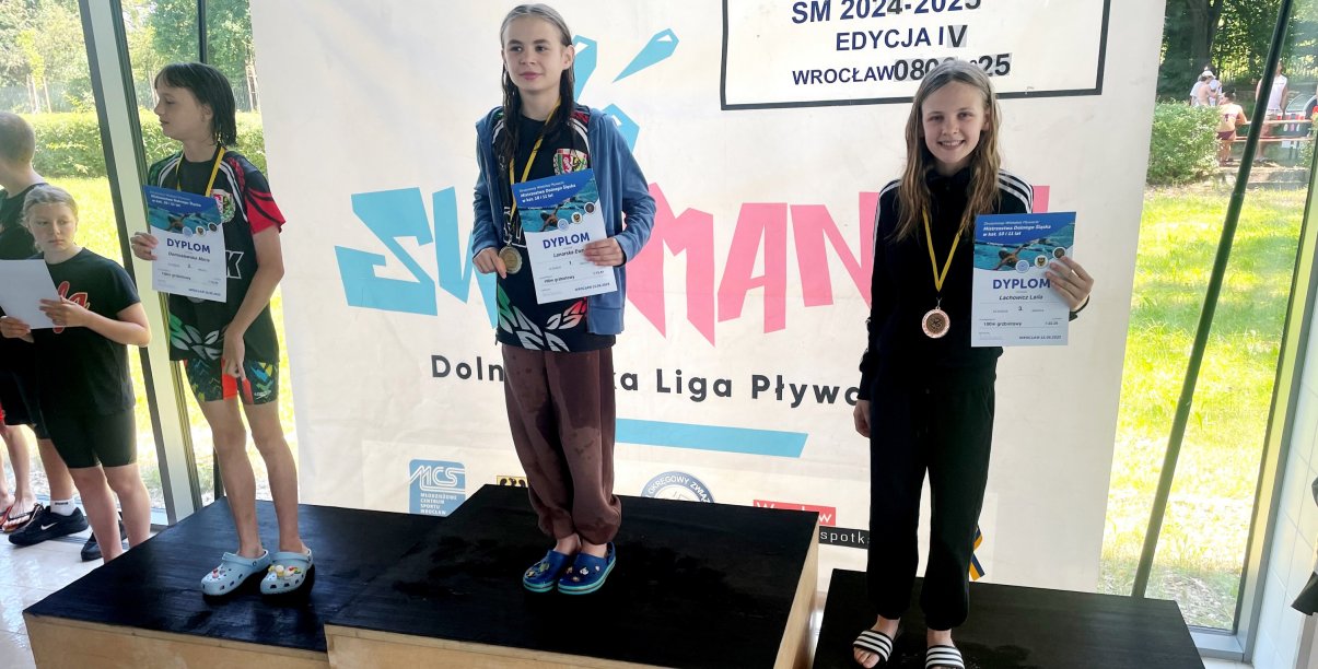 Laila Lachowicz na najwyższym stopniu podium z medalem i dyplomem, po bokach dwie pływaczki