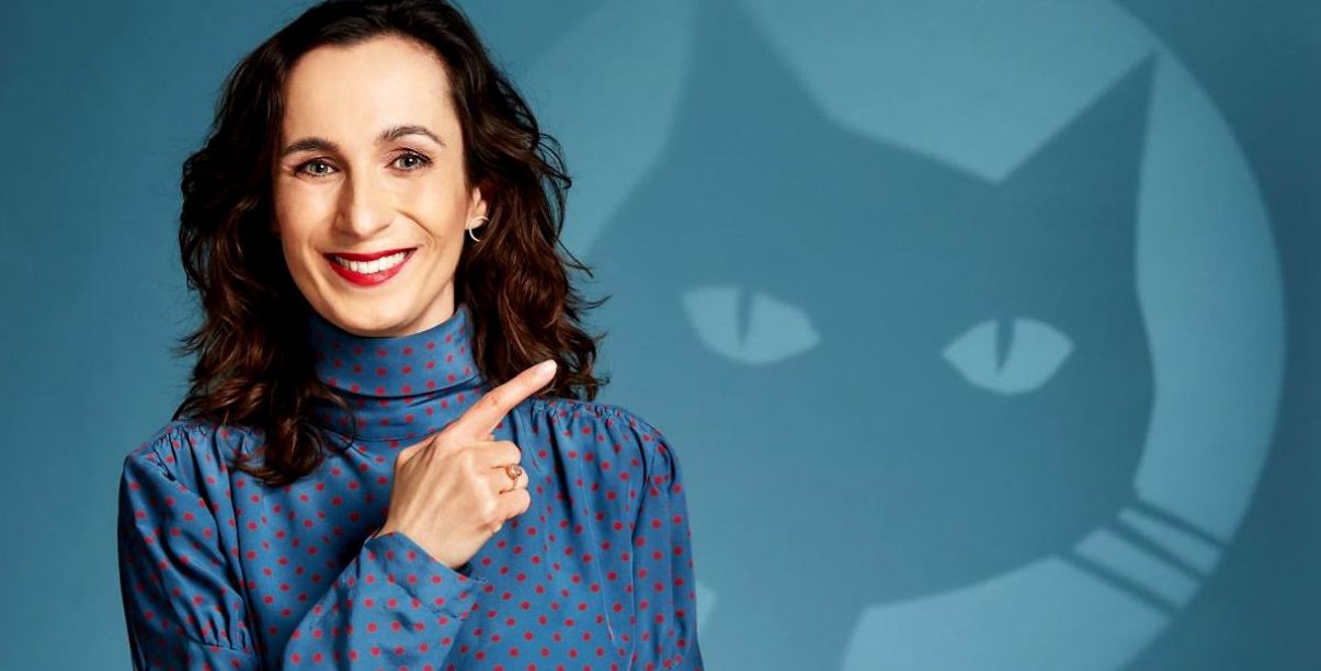 Agata Romaniuk wskazująca palcem na grafikę kota