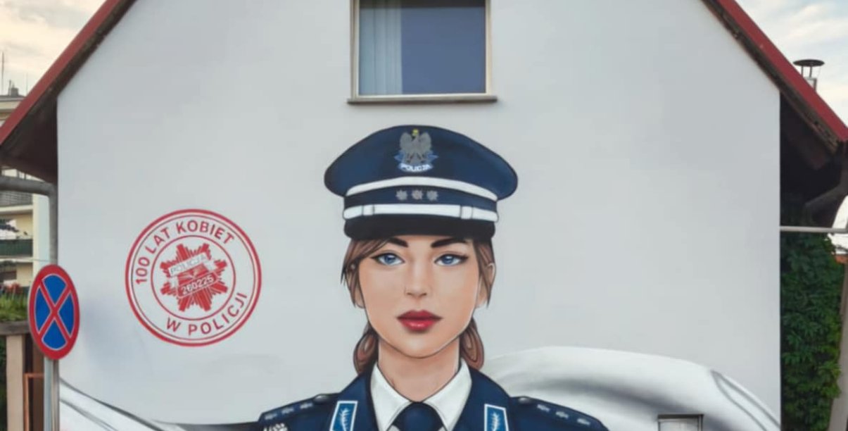 Malowidło na fasadzie budynku, przedstawiające kobietę policjantkę w mundurze, w tle polska flaga i napis 100 lat kobiet w policji