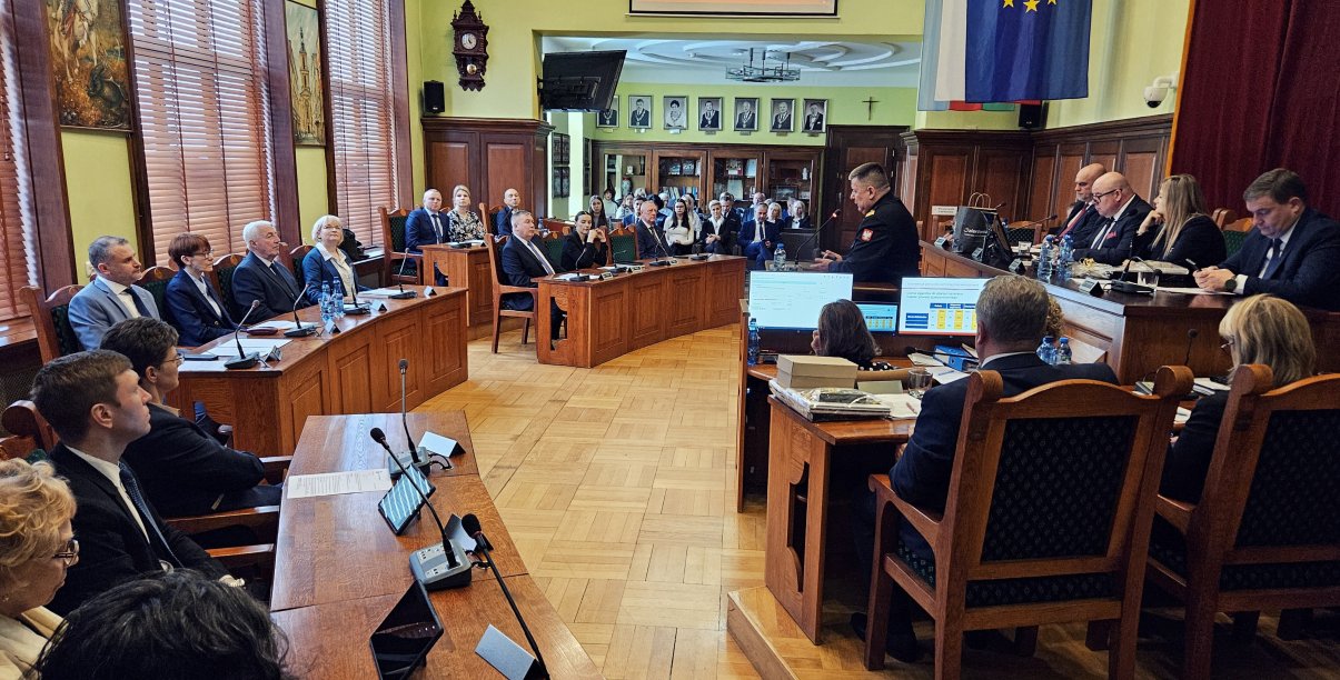 Sala Rycerska podcza sesji, radni siedzący przy stołach, po prawej stół prezydialny, w drugim planie widownia