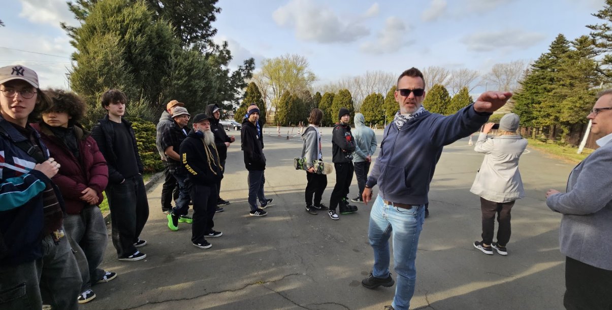 Grupa mężczyzn na placu manewrowym, jeden z nich coś pokazuje ręką
