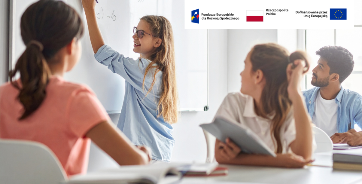 Grupa uczniów w klasie, jedna z uczennic pisze po tablicy