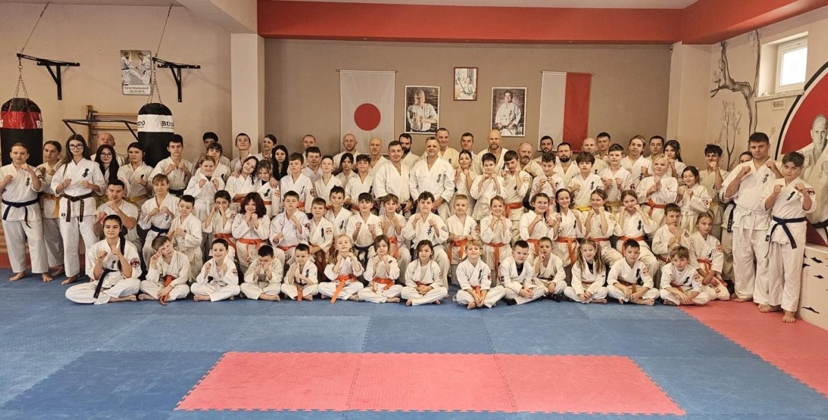 Duża grupa zawodników karate w kimonach na macie sportowej
