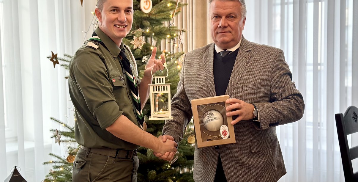 ć zdjęcie przedstawiające moment przekazania światła, burmistrza z komendantem Tomaszem Tkaczem przy płomieniu