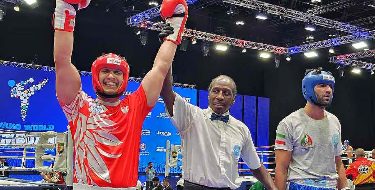 Maks Palej na ringu z uniesionymi rękami w geście zwycięstwa, obok sędzia i przeciwnik