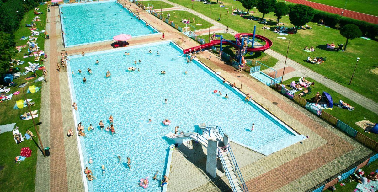 zdjęcie z lotu ptaka, dwie niecki basenowe na terenie OSiR-u, w wodzie kąpiący się ludzie