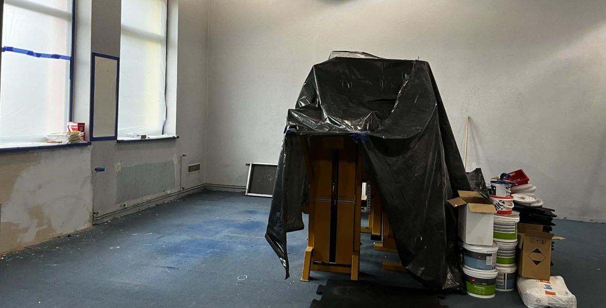 Pomieszczenie siłowni w remoncie, sprzęty zakryte folią malarską
