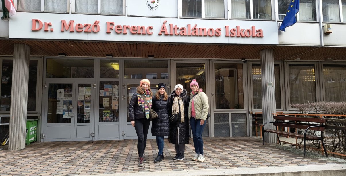 Trzy kobiety przed budynkiem szkoły