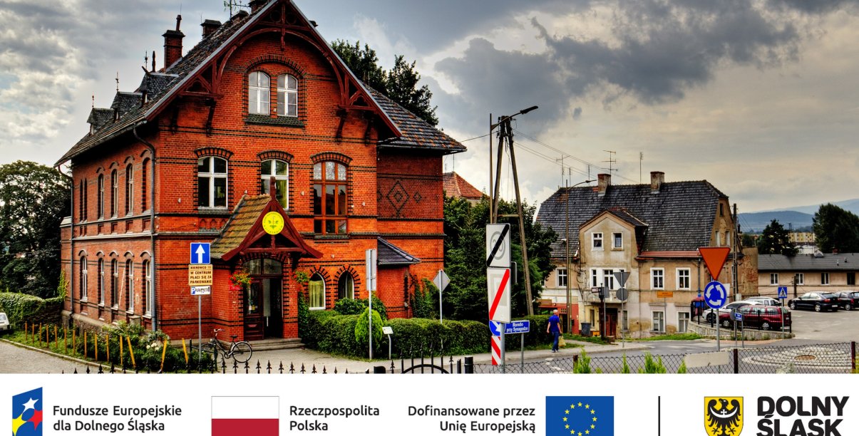 Budynek z czerwonej cegły, u dołu logotypy partnerów projektu