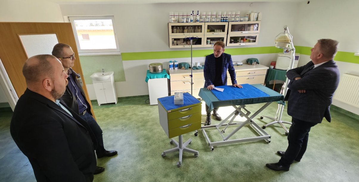 czterecvh mężczyzn w ambulatorium dla zwierząt, stoją wokół stołu zabiegowego, oglądają pomieszczenie 