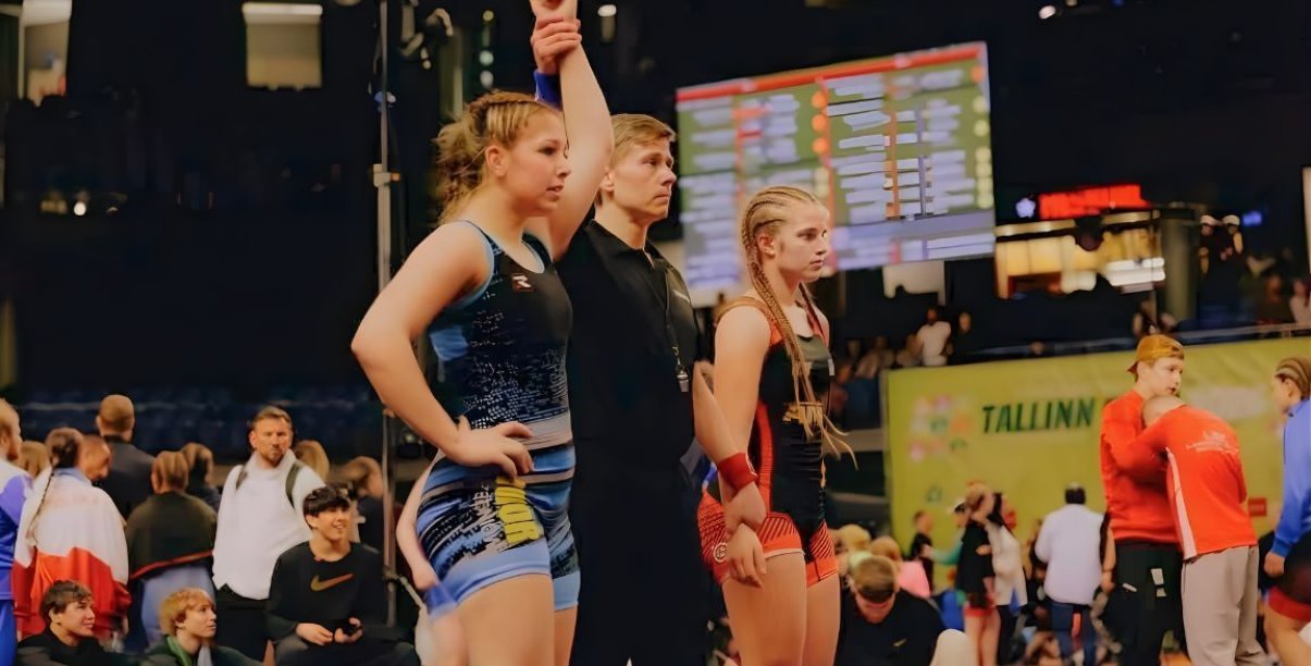 Dwie zapaśniczki, po środku sędzia unoszący rękę zwyciężczyni walki