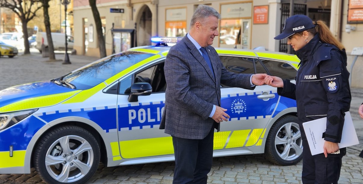 Burmistrz wręczający kluczyki policjantce, w tle nowy radiowóz