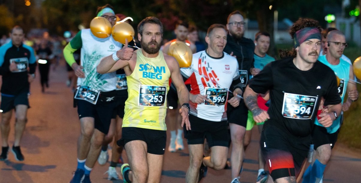 Kilkanaście osób biegnących nocą po ulicy