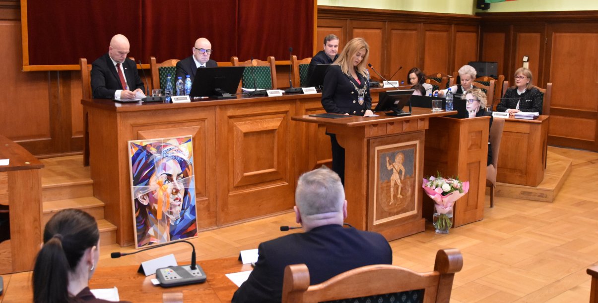 Sesja, przy mównicy przewodnicząca rady, za nią stół prezydialny i trzech wiceprzewodniczących