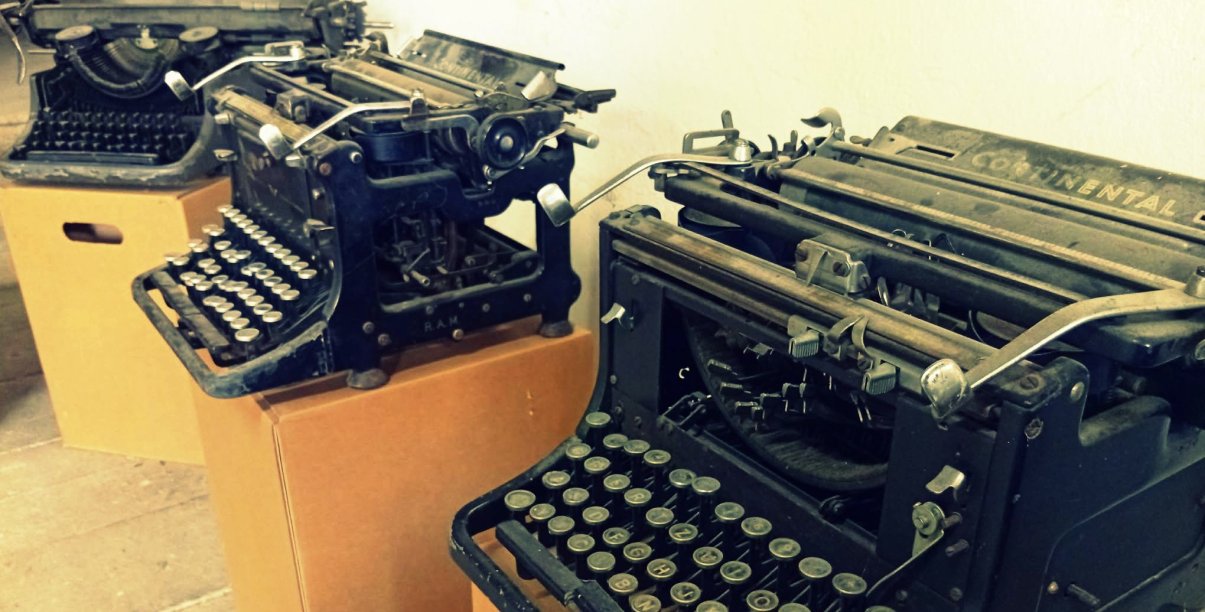 Trzy stare maszyny do pisania na kartonowych pudełkach