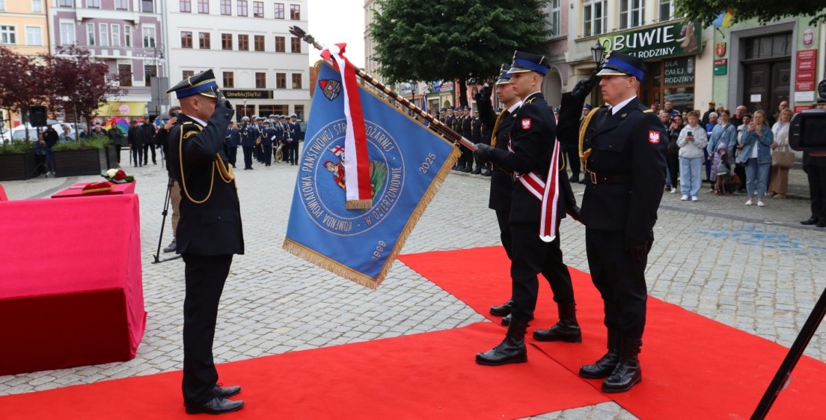 Oficer straży pożarnej salutuje przed sztandarem
