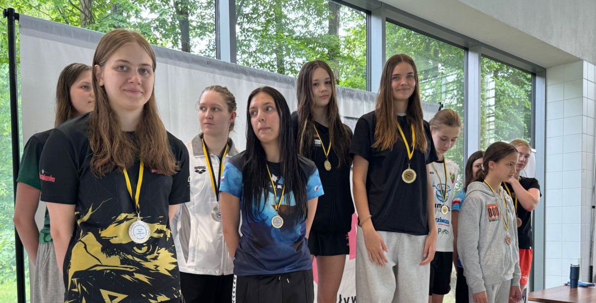 Grupa pływaczek na wspólnym zdjęciu, każa ma na szyi medal