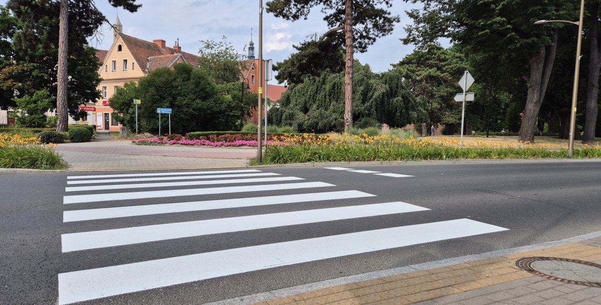 Przejście dla pieszych zaraz po namalowaniu, za przejściem mała kamienica i park