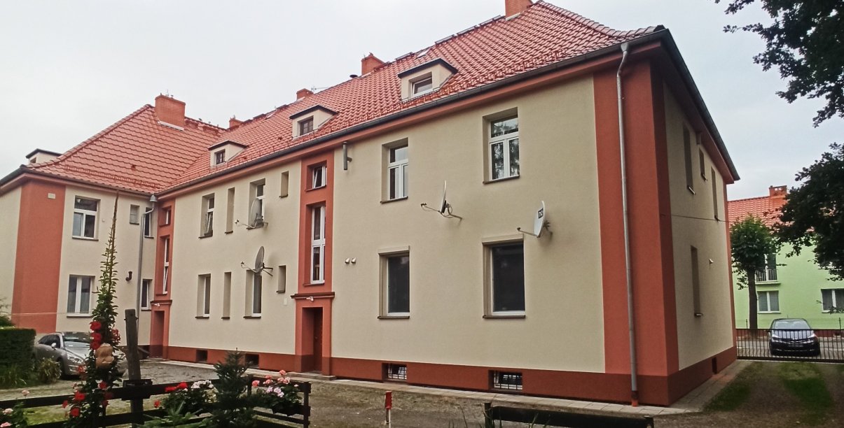 Dwupiętrowa kamienica z odnowioną elewacją w piaskowym kolorze z brązowymi elementami