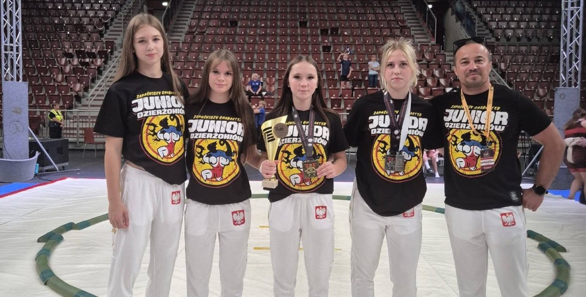 Cztery zawodniczki i trener na białej macie do walk sumo