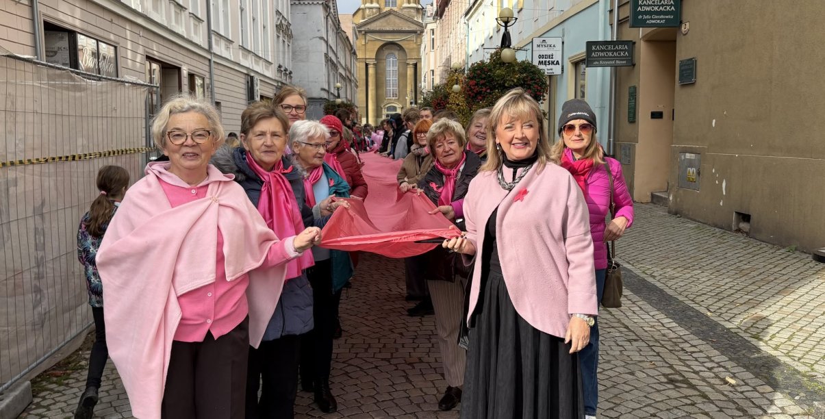 kobiety ubranwe na różowo niosą wielką różową wstęgę