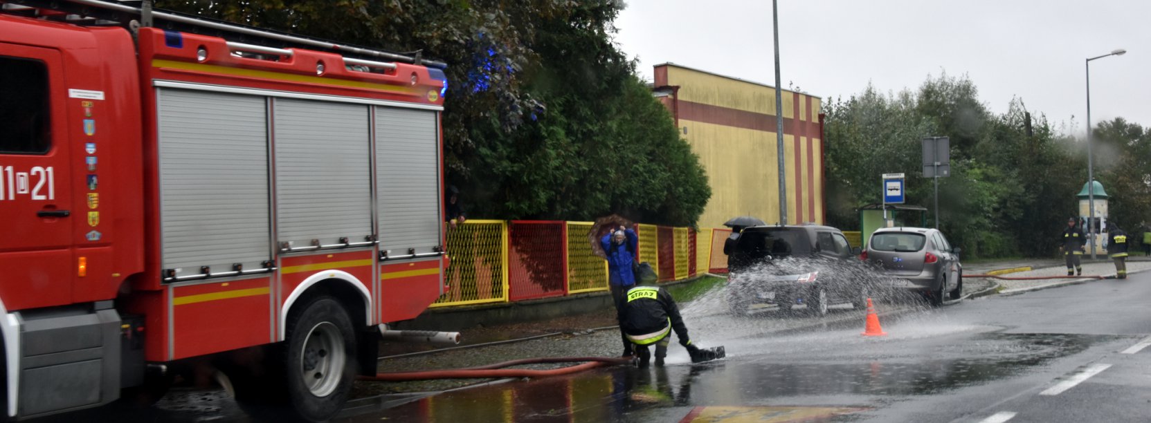 Strażakpracujący przy wypompowywaniu wody ze studzienki 