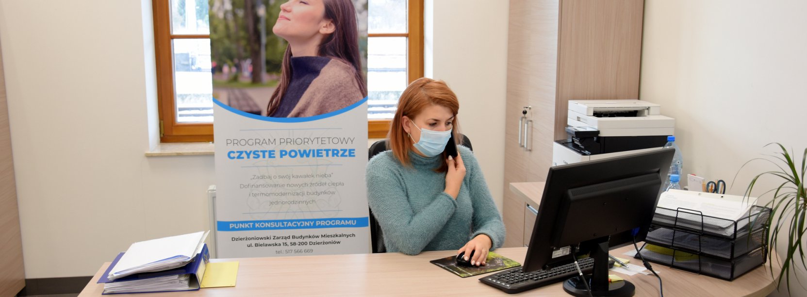 Osoba za biurkiem rozmawiająca przez telefon w siedzibie biura.